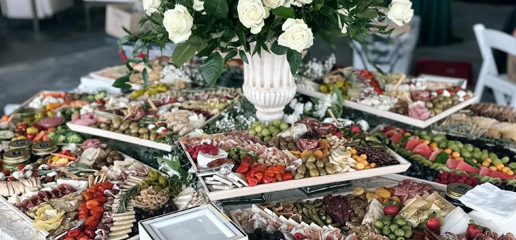 A Graze Craze grazing table layered with cured meats, cheeses, fruit and florals
